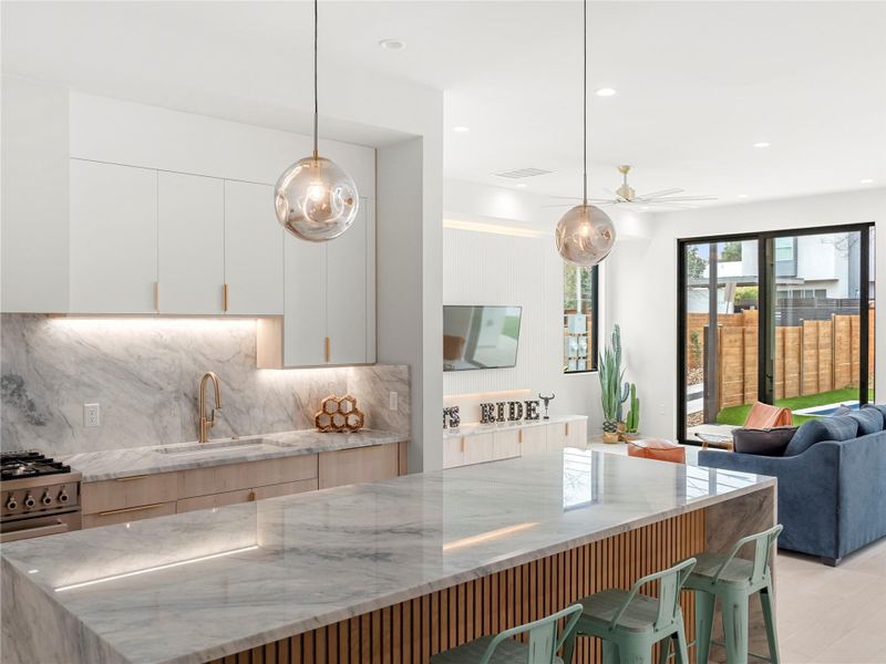 Two tone kitchen with light stone countertops, tasteful backsplash, decorative light fixtures, modern cabinets, and two tone cabinets