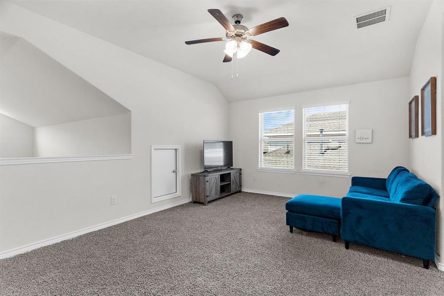 Living area featuring a ceiling fan, lofted ceiling, baseboards, visible vents, and carpet