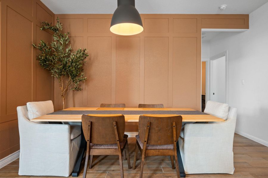 Dining space with light wood-style floors and a decorative wall Dining space with light wood-style floors and a decorative wall
