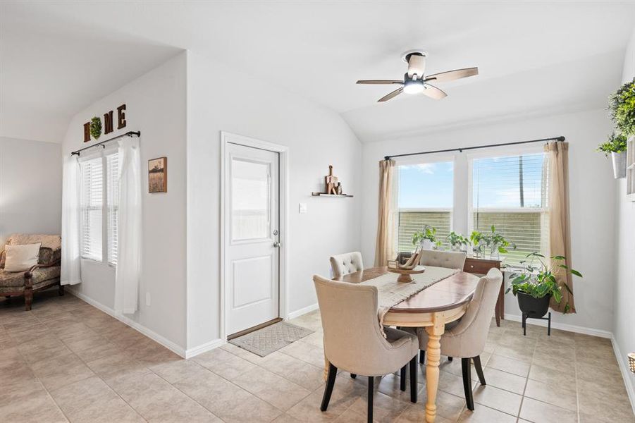 Dining room with vaulted ceiling, ceiling fan, plenty of natural light, and light tile patterned floors
