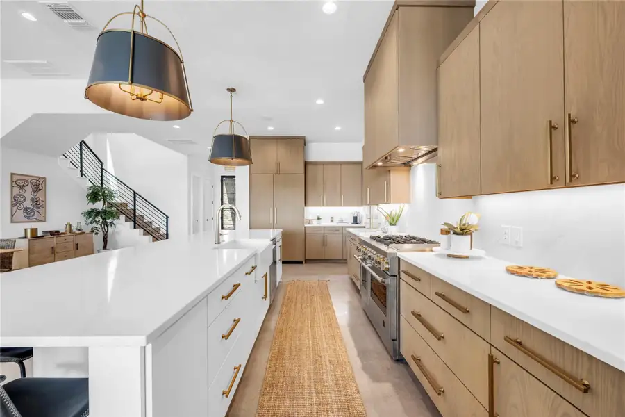 Gleaming quartz countertops pair with custom wood cabinetry in this airy chef kitchen.