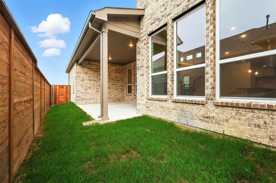 View of side of home with a patio area, a fenced backyard, and brick siding