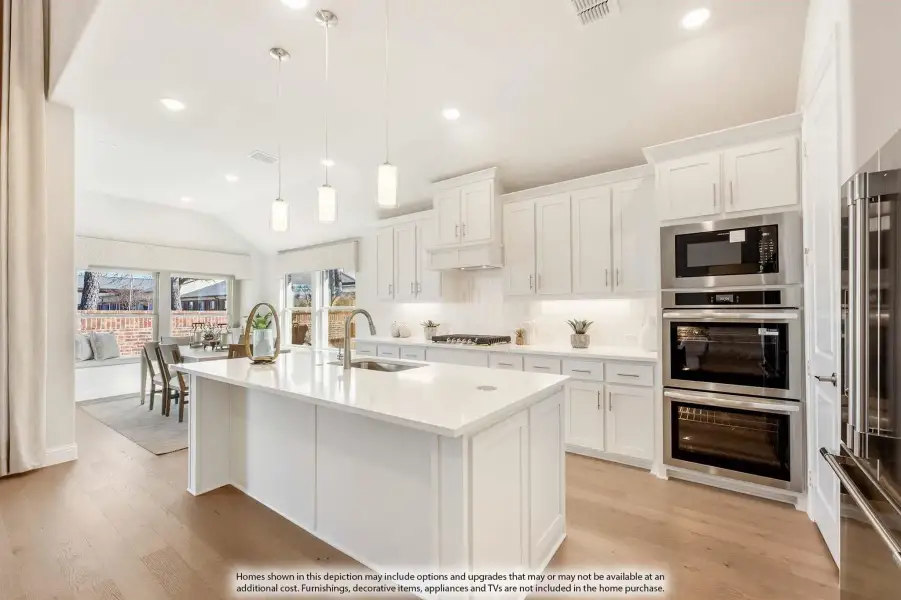 Kitchen with white cabinets, large island with sink, stainless steel double oven, and hardwood floors