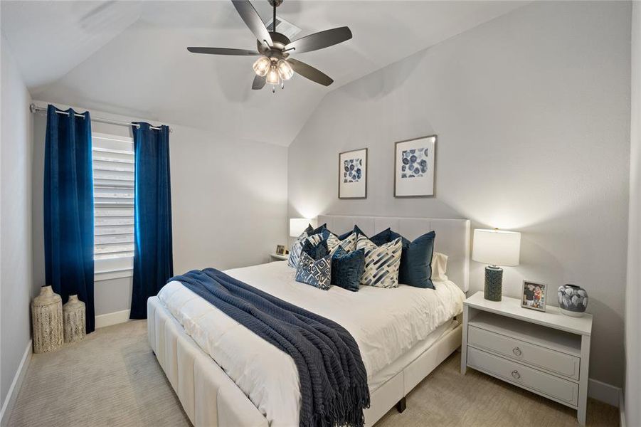 Carpeted bedroom with ceiling fan and lofted ceiling