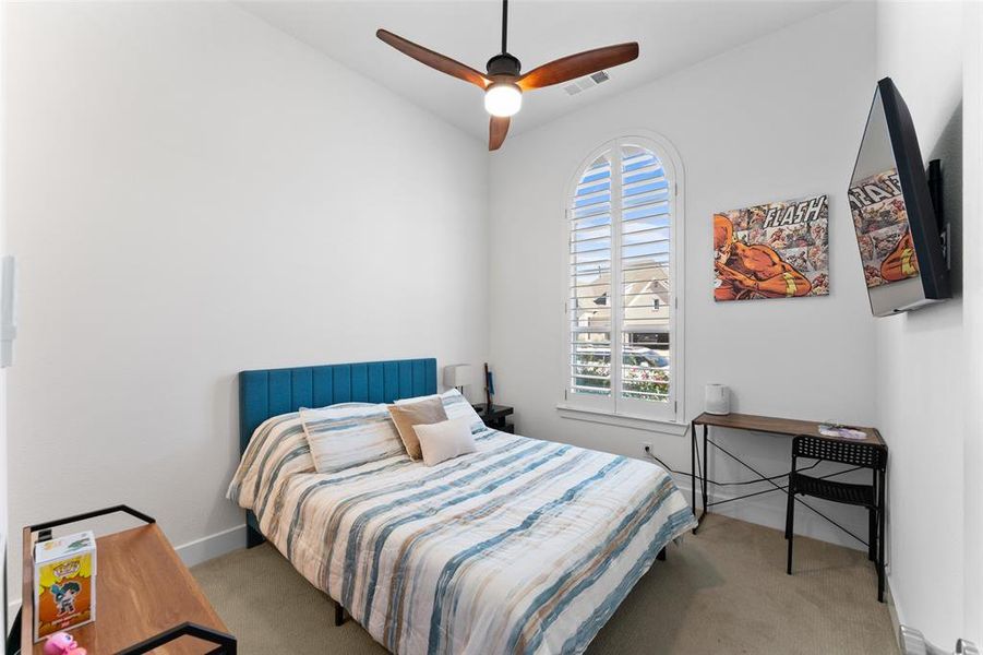 This room features a high vaulted ceiling, an arched window with plantation shutters, and a ceiling fan