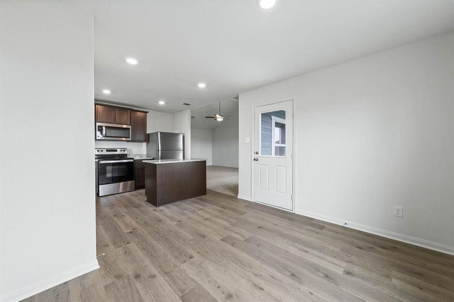 Kitchen with dark brown cabinets, light countertops, appliances with stainless steel finishes, a kitchen island, and recessed lighting Kitchen with dark brown cabinets, light countertops, appliances with stainless steel finishes, a kitchen island, and recessed lighting