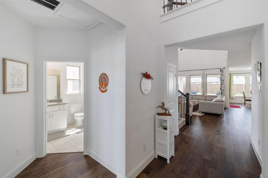 Hall featuring a sink, dark wood finished floors, visible vents, and baseboards