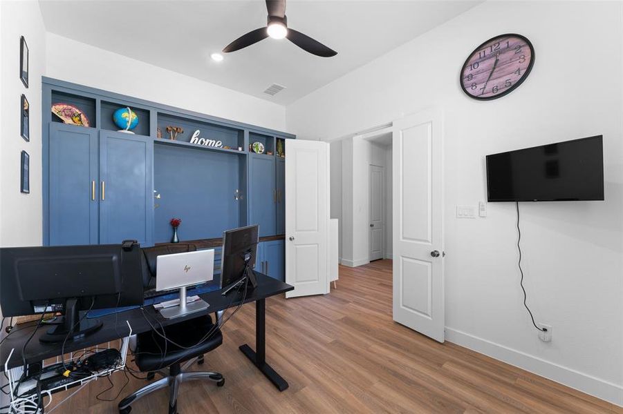 This room features wood-look flooring, a ceiling fan, and a built-in blue storage unit with shelving