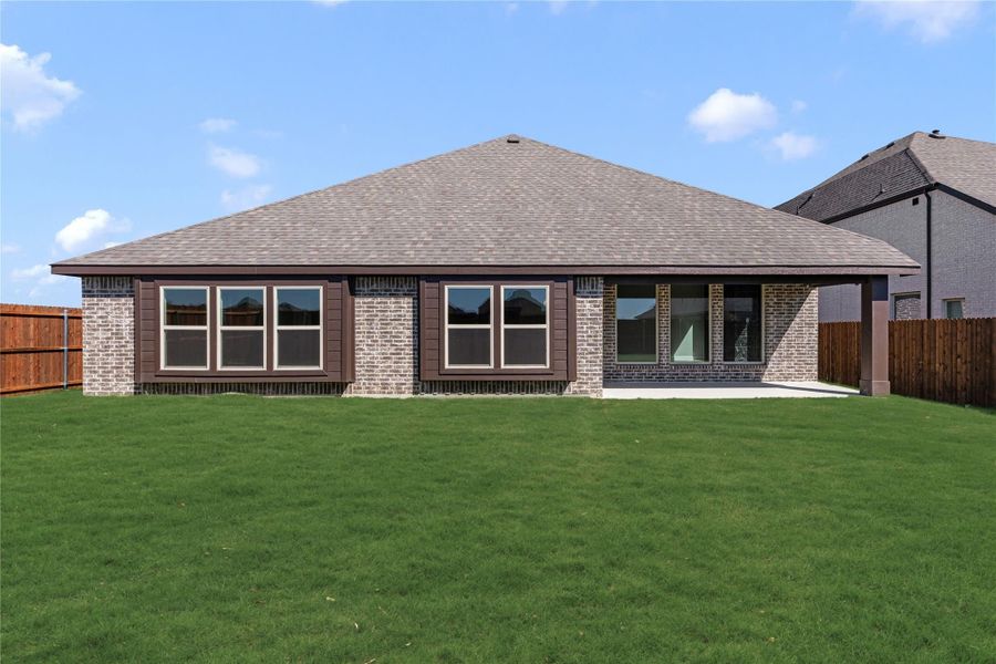 Rear exterior of single-story brick home with hip roof, large windows, patio, and fenced backyard lawn. Rear exterior of single-story brick home with hip roof, large windows, patio, and fenced backyard lawn.