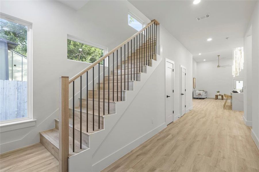 Stairway featuring wood finished floors, recessed lighting, healthy amount of natural light, a ceiling fan, and baseboards Stairway featuring wood finished floors, recessed lighting, healthy amount of natural light, a ceiling fan, and baseboards