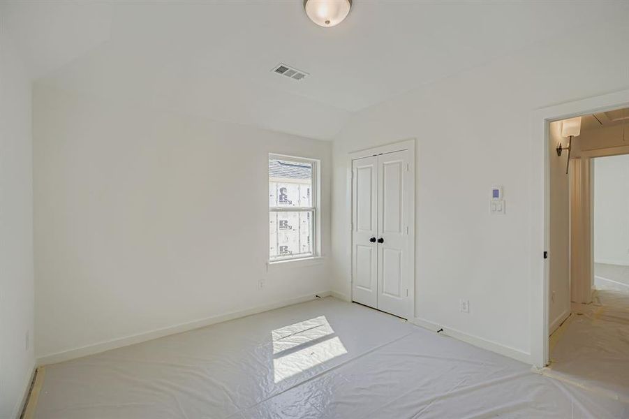 Unfurnished bedroom featuring lofted ceiling, a closet, attic access, and carpet flooring Unfurnished bedroom featuring lofted ceiling, a closet, attic access, and carpet flooring