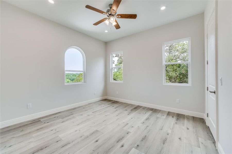 Empty room featuring ceiling fan, plenty of natural light, and light hardwood / wood-style flooring