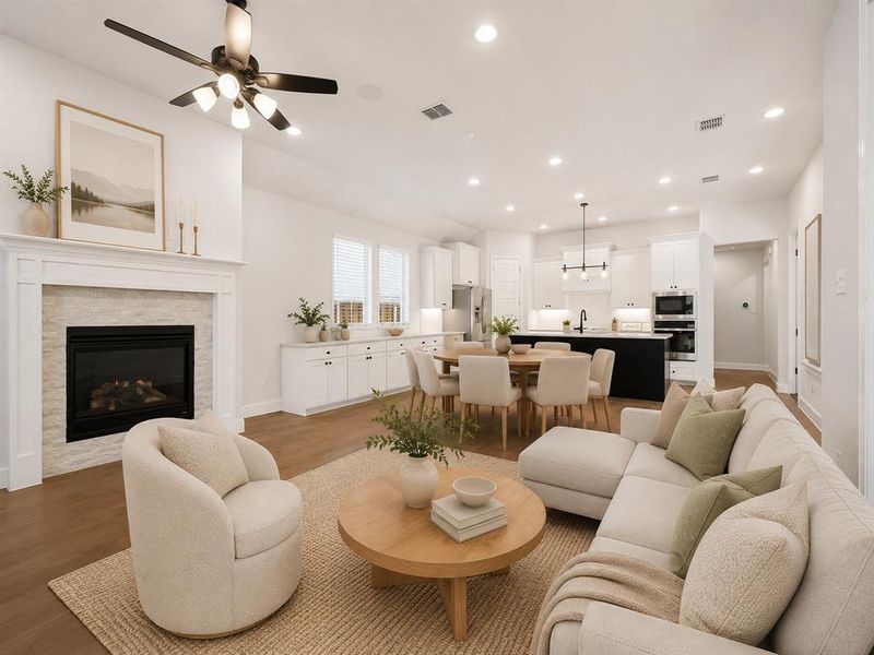 Open-concept living area featuring hardwood flooring, a contemporary fireplace with a stone surround and white mantel, and recessed lighting