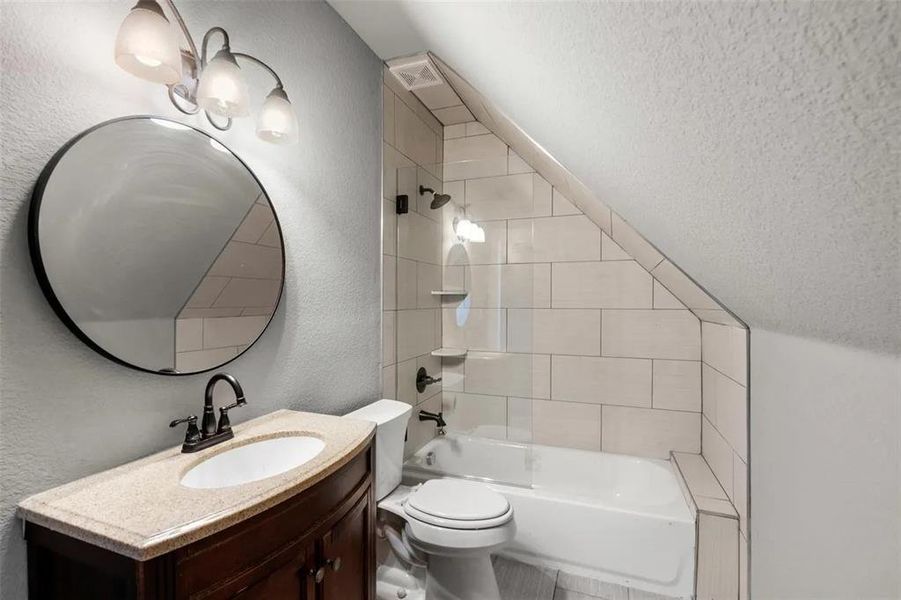 Full bathroom featuring a textured wall, shower / bathtub combination, vanity, and a textured ceiling