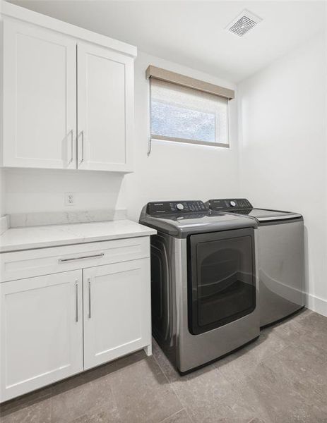 Laundry room with washing machine and clothes dryer, cabinets, and tile patterned floors