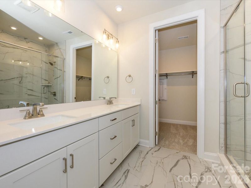 Dual vanity primary bathroom with walk-in closet