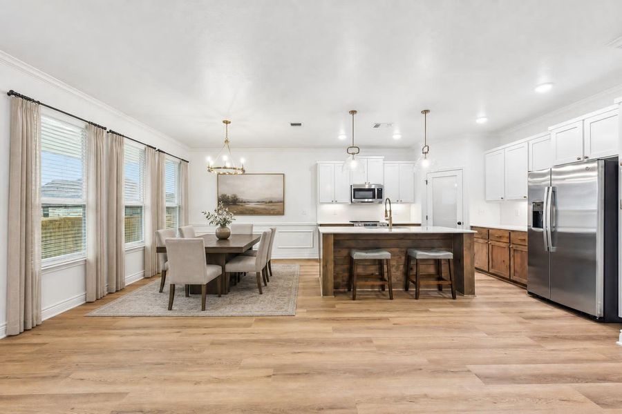An open-concept layout unites the kitchen and dining areas, illuminated by pendant and chandelier lighting. Virtually staged. An open-concept layout unites the kitchen and dining areas, illuminated by pendant and chandelier lighting. Virtually staged.