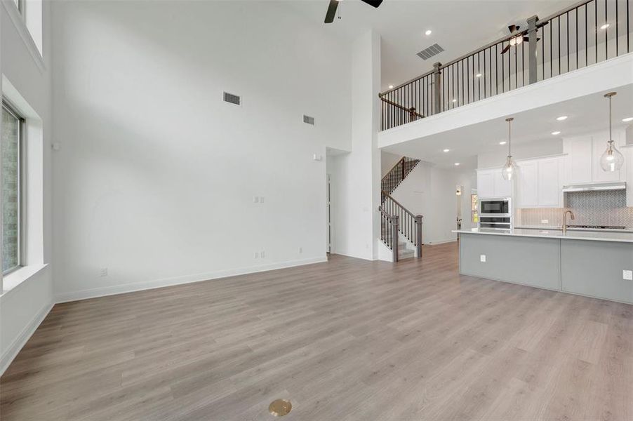 Open-concept living space with wood-finish flooring, soaring ceilings, and abundant natural light Open-concept living space with wood-finish flooring, soaring ceilings, and abundant natural light
