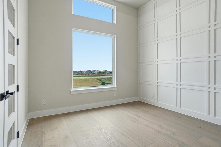 Private office featuring decorative wall trim, tall windows for natural light, and architectural ceiling detail.