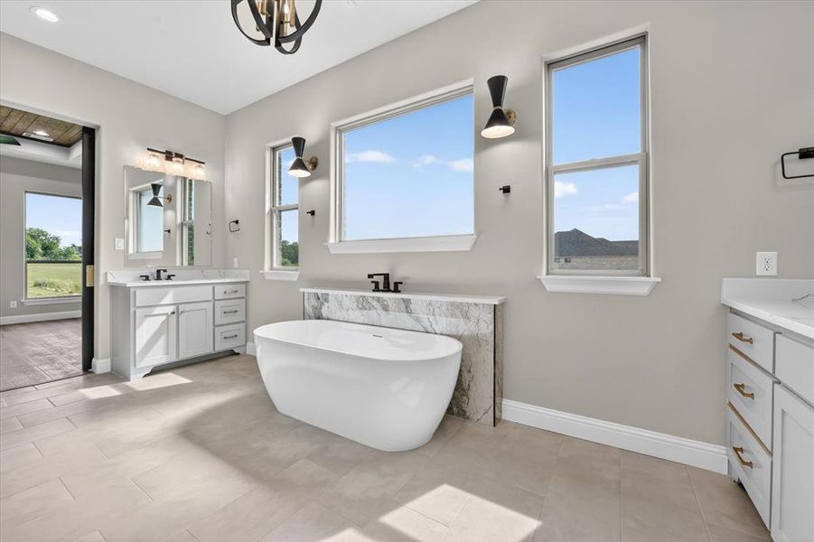 Freestanding soaking tub with a marble-clad surround, flanked by large windows