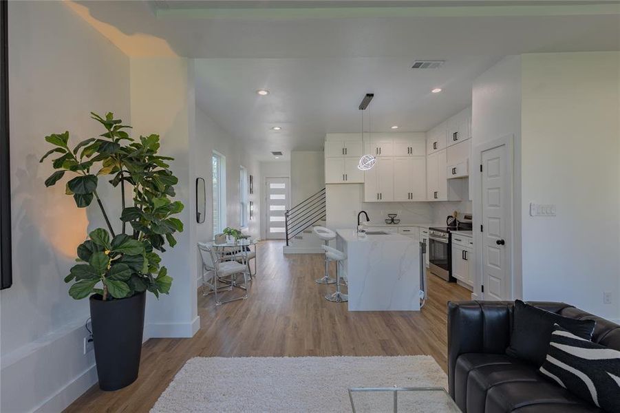 Living room featuring light wood-style floors, stairway, and recessed lighting Living room featuring light wood-style floors, stairway, and recessed lighting