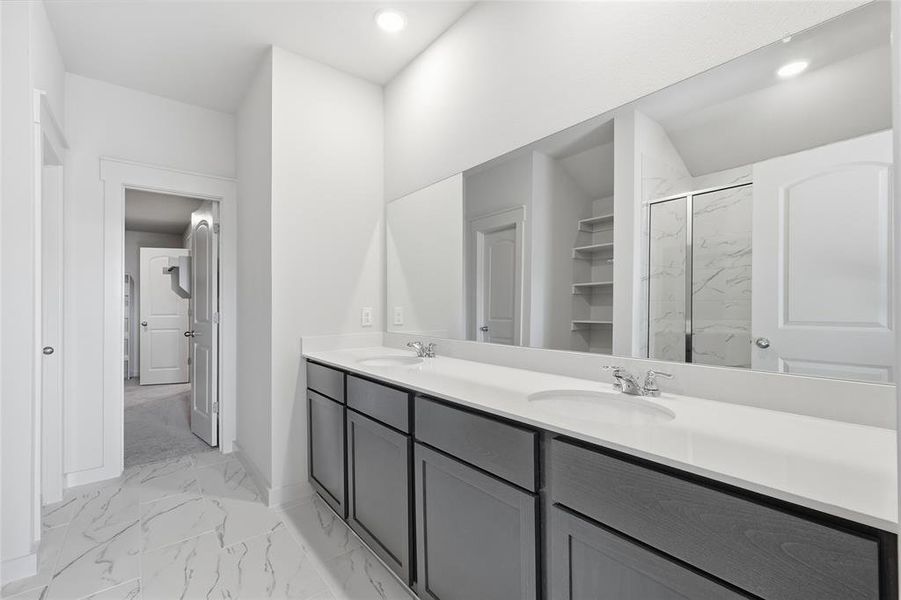 Bathroom with a marble finish shower, light marble finish flooring, double vanity, a walk in closet, and recessed lighting