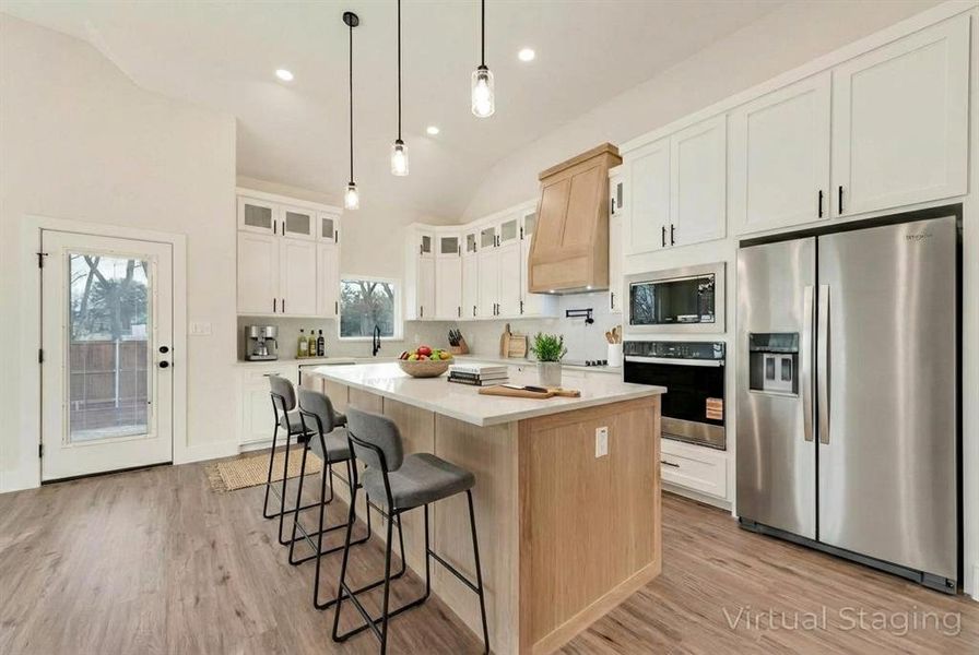 Virtually Staged Furniture Kitchen featuring stainless steel appliances, glass insert cabinets, a kitchen bar, hanging light fixtures, and a center island