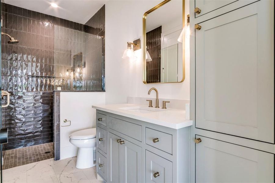 Full bathroom featuring marble finish floor, toilet, vanity, and tiled shower