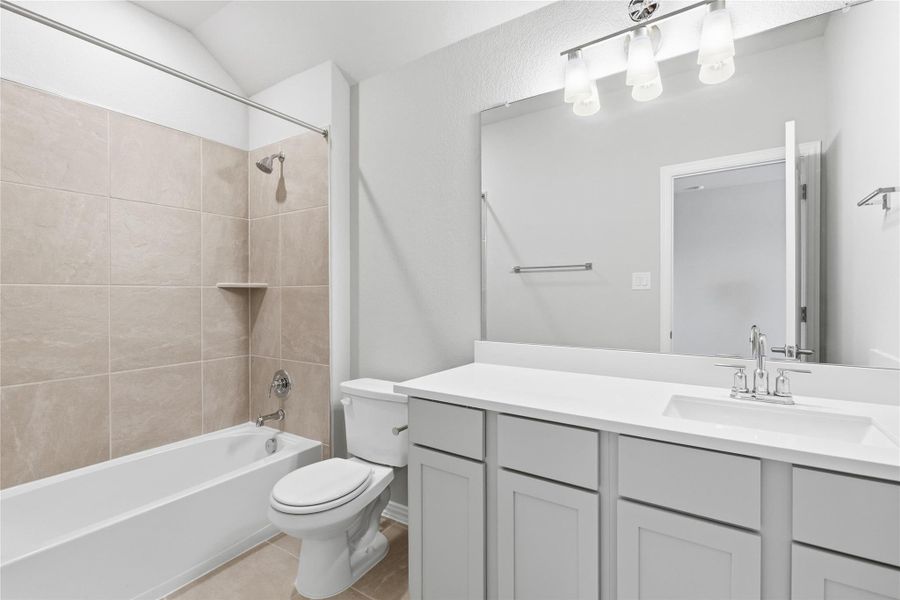 Bathroom featuring washtub / shower combination, vanity, and light tile patterned floors
