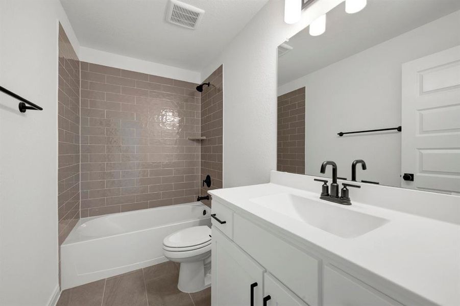 Bathroom featuring a white vanity with integrated sink, matte black faucet, and a large mirror with sconce lighting