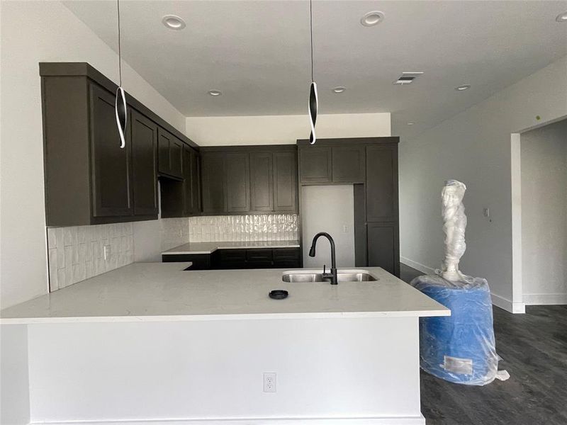 Kitchen featuring pendant lighting, tasteful backsplash, dark hardwood / wood-style floors, and sink