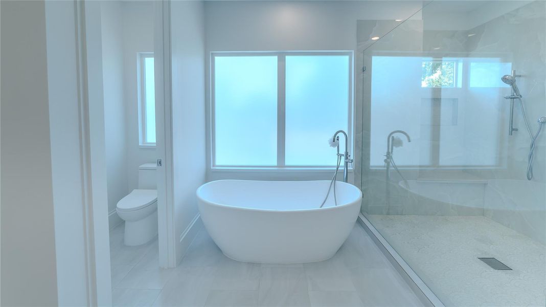 This bathroom features a modern design with a freestanding bathtub, a spacious glass-enclosed shower, and frosted windows for privacy. The space is bright and airy, creating a relaxing atmosphere.