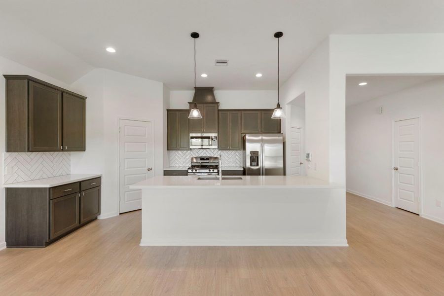 Rich, dark cabinetry pairs with crisp white countertops and a sleek backsplash to create a clean, inviting kitchen.