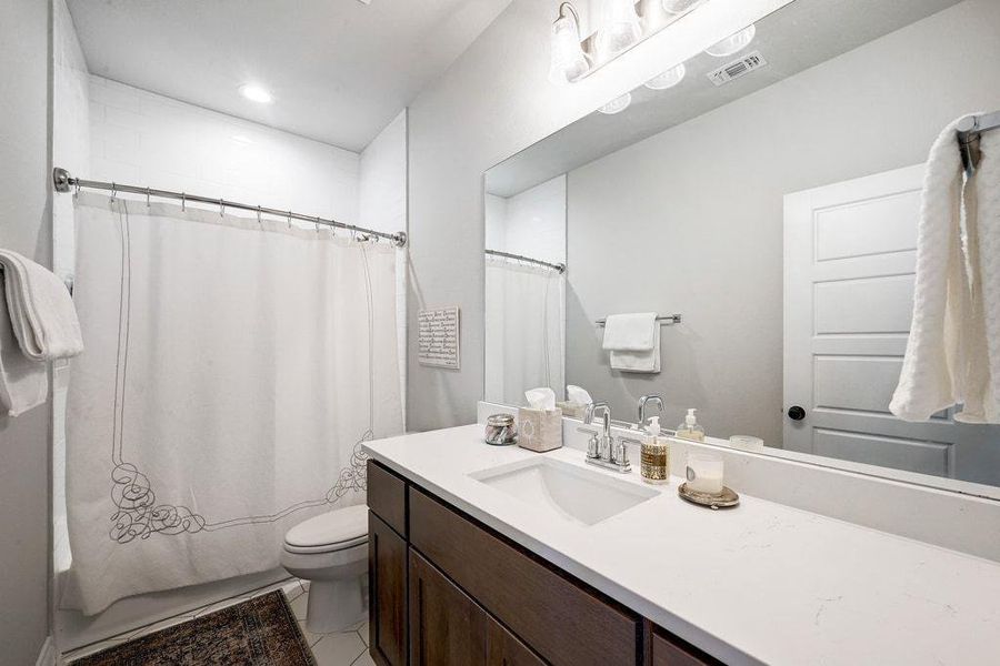 Full bathroom with vanity, light tile patterned flooring, and shower / bath combination Full bathroom with vanity, light tile patterned flooring, and shower / bath combination