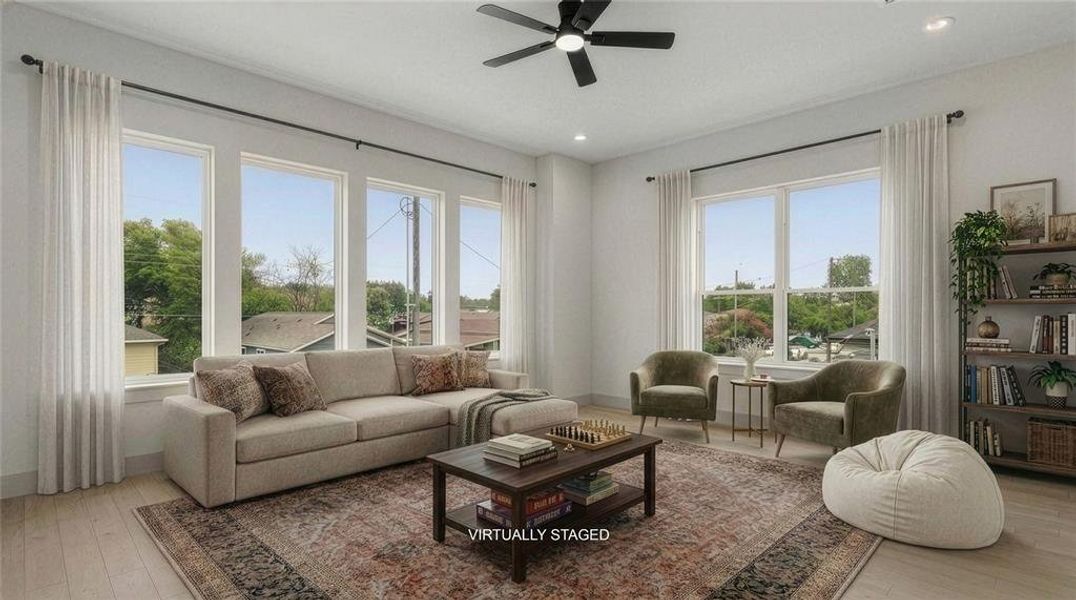 Spacious second level game room featuring light wood-finish flooring, a contemporary black ceiling fan, recessed lighting, and a wall of four large windows. Spacious second level game room featuring light wood-finish flooring, a contemporary black ceiling fan, recessed lighting, and a wall of four large windows.