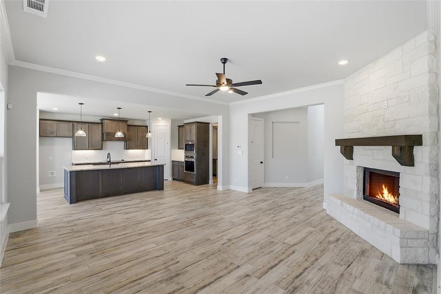 Unfurnished living room with ornamental molding, a fireplace, a ceiling fan, light wood finished floors, and recessed lighting