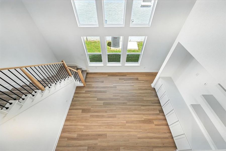 Unfurnished living room featuring a towering ceiling, stairs, and light wood finished floors