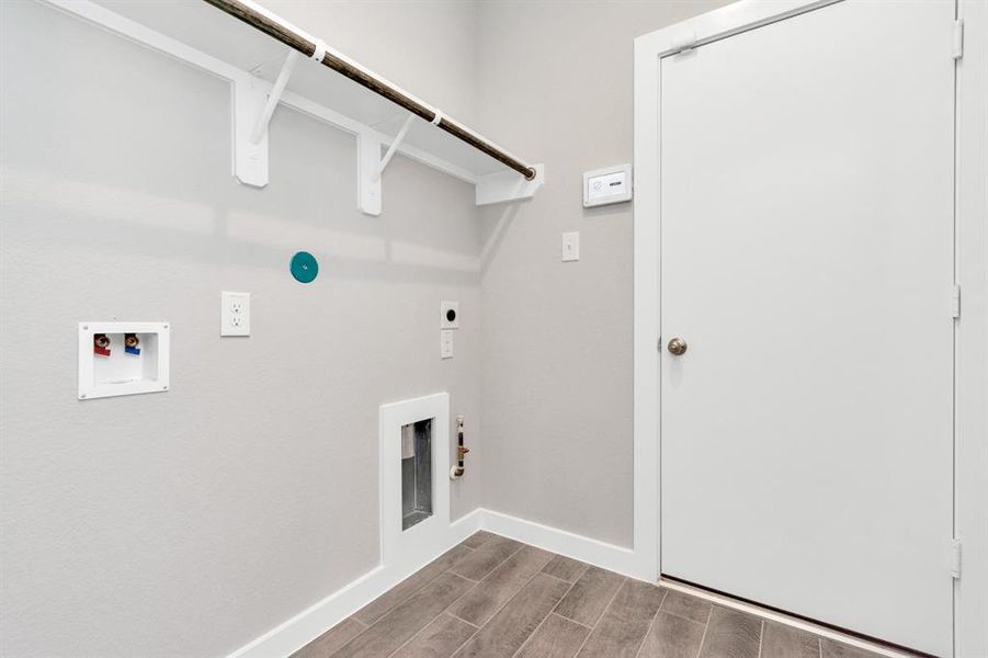 Located on first floor, a stylish laundry room where practicality meets a contemporary aesthetic. The dark finishes lend a sophisticated touch, creating a space that is both functional and visually appealing. Both electric and gas connections available. Sample photo of completed home with similar floor plan. As-built interior colors and selections may vary.