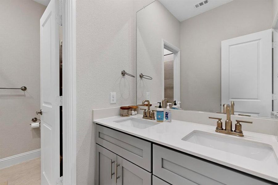 Bathroom featuring double vanity and baseboards Bathroom featuring double vanity and baseboards