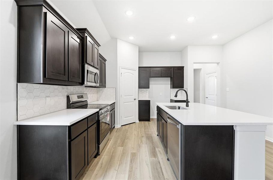 Kitchen with stainless steel appliances, tasteful backsplash, light stone countertops, light wood-style flooring, and recessed lighting