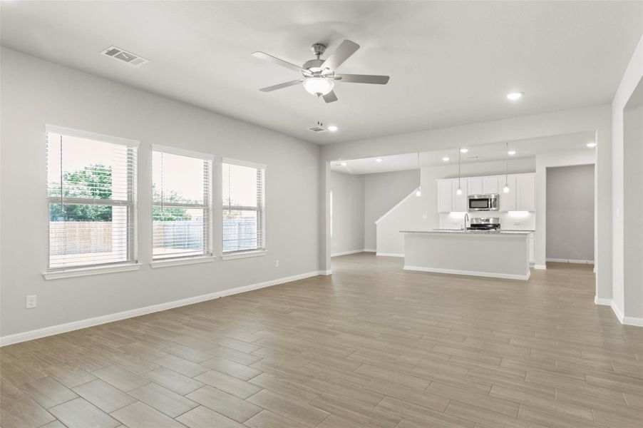 Unfurnished living room with a ceiling fan, recessed lighting, baseboards, and light wood-style flooring