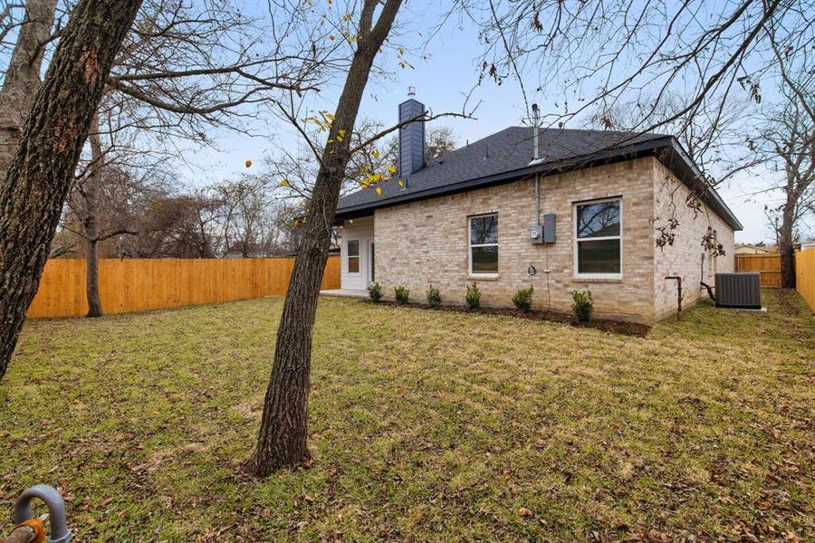 Rear view of house with a lawn and central air condition unit