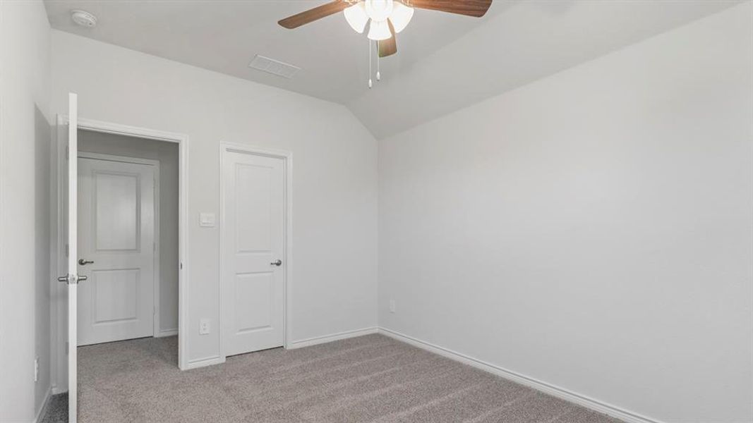 Unfurnished bedroom featuring carpet floors, vaulted ceiling, and ceiling fan