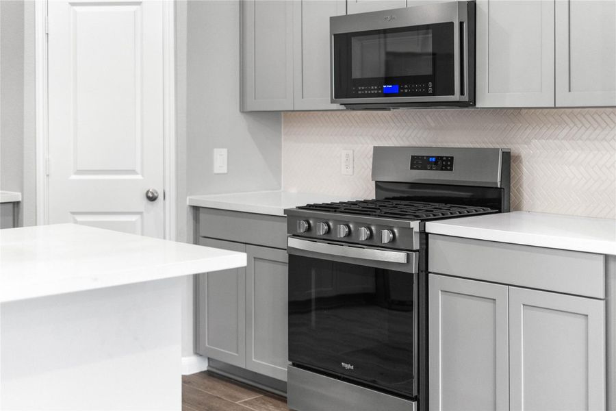 Showcased here is a Whirlpool gas range, paired with a steam microwave equipped with sensor cooking—all framed by an elegant tile backsplash.