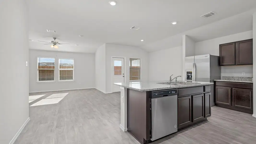Kitchen with dark brown cabinetry, open floor plan, stainless steel dishwasher, light wood-style flooring, and recessed lighting