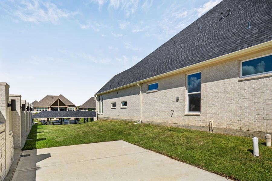 Side yard with concrete pad and gated access, ideal for boat or trailer parking or additional storage.