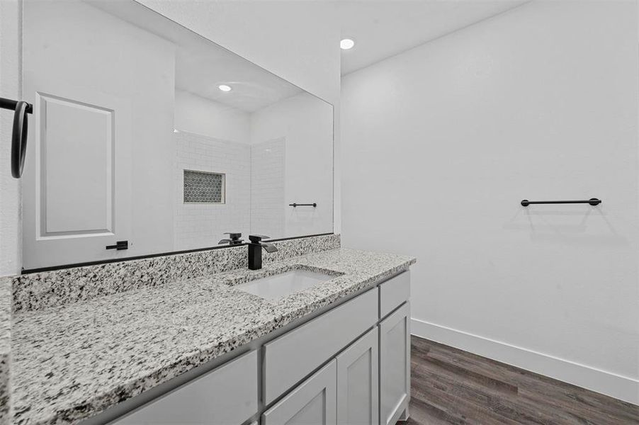 Bathroom featuring vanity, wood-type flooring, and tiled shower