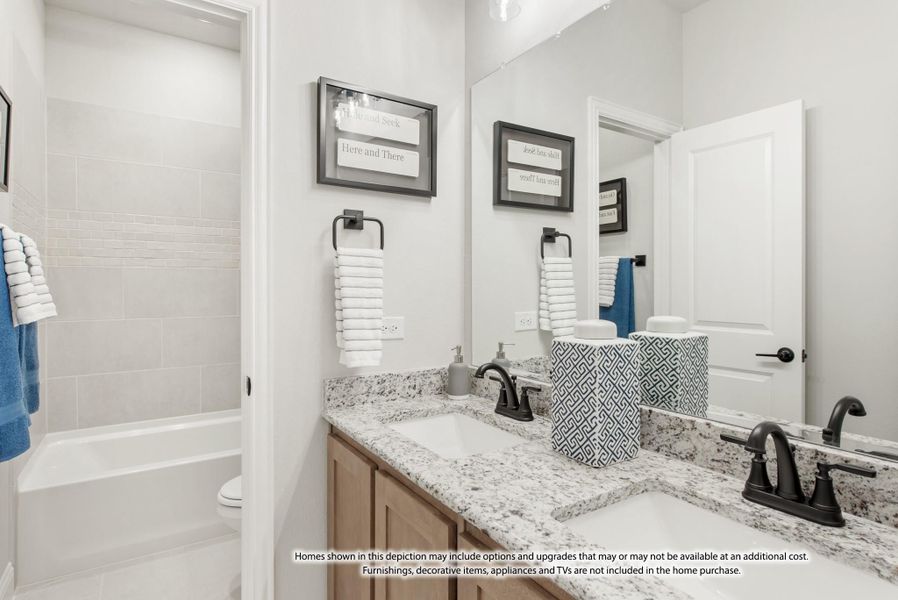 Shared bathroom with double vanity, granite countertops, wood cabinets, and tiled tub-shower combo Shared bathroom with double vanity, granite countertops, wood cabinets, and tiled tub-shower combo