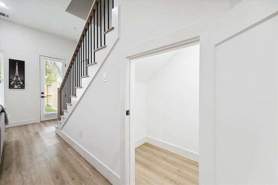 A peek at the cleverly positioned storage closet beneath the staircase, perfect for maximizing functionality. To the left, the door opens to a spacious 20x20 yard, ideal for outdoor living and entertaining.