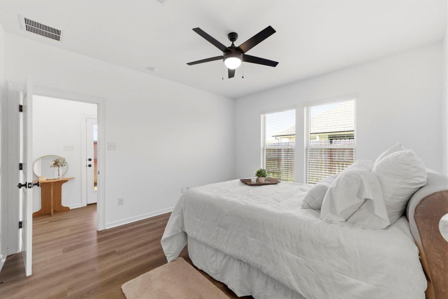 Light-filled primary bedroom offering a spacious layout, ceiling fan, and luxury vinyl plank flooring.